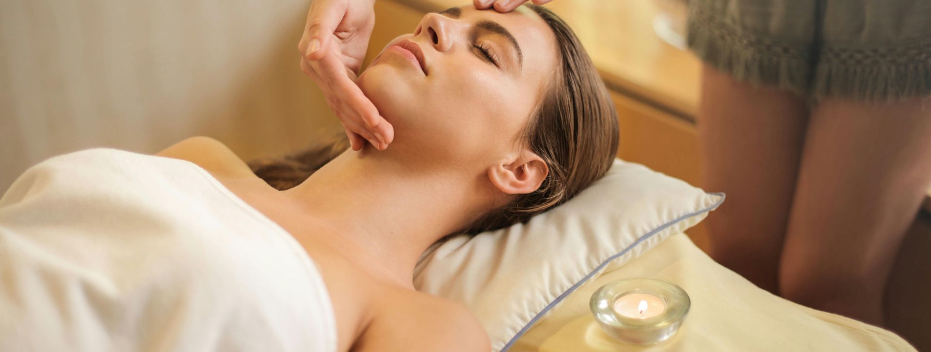 Woman in Wrapped in White Towel Lying on Bed Getting Massage